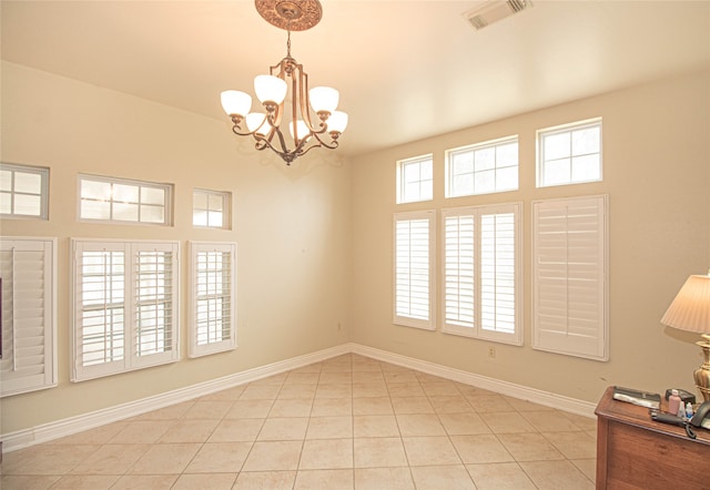 empty room featuring a notable chandelier and light tile patterned flooring