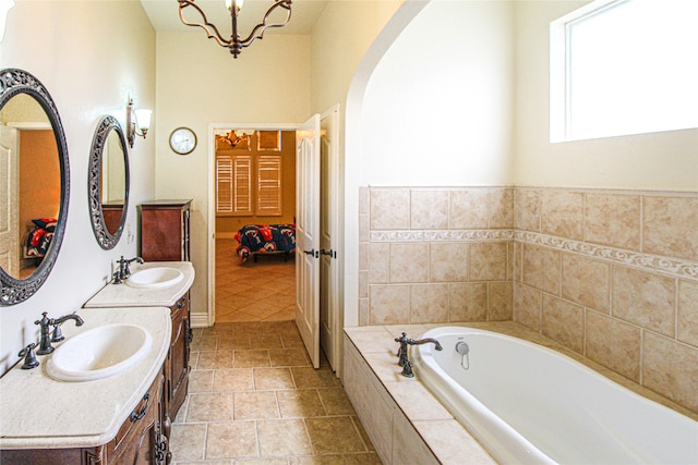 bathroom featuring vanity, a relaxing tiled tub, tile patterned floors, and an inviting chandelier