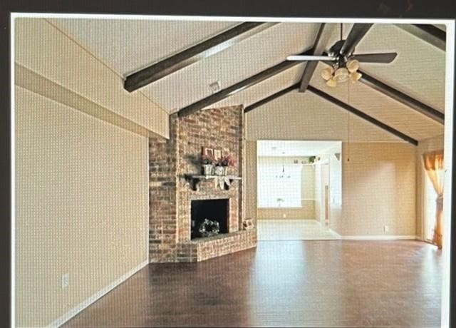 unfurnished living room with high vaulted ceiling, brick wall, a brick fireplace, ceiling fan, and beamed ceiling