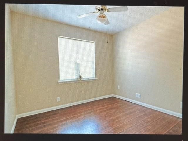 empty room with dark wood-type flooring and ceiling fan