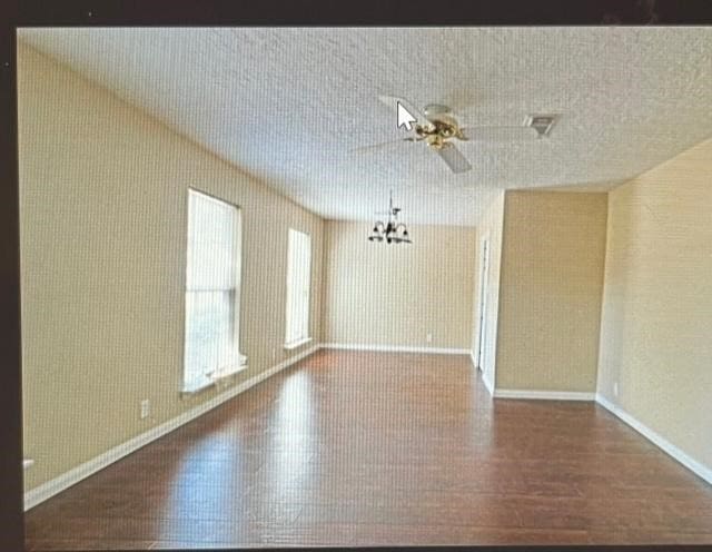 spare room with dark hardwood / wood-style floors and ceiling fan with notable chandelier