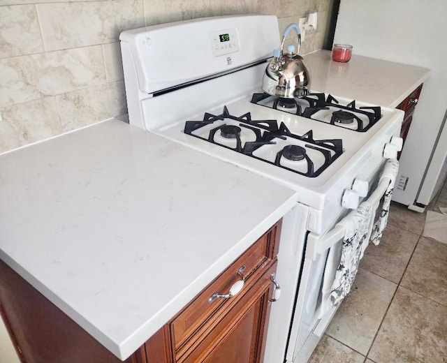 kitchen featuring white range with gas stovetop, tile walls, and light tile flooring