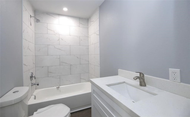 full bathroom featuring tiled shower / bath combo, toilet, and vanity