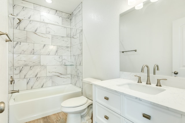 full bathroom with tiled shower / bath, large vanity, toilet, and hardwood / wood-style floors