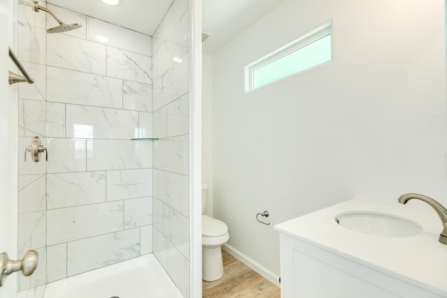 bathroom featuring tiled shower, vanity, toilet, and wood-type flooring