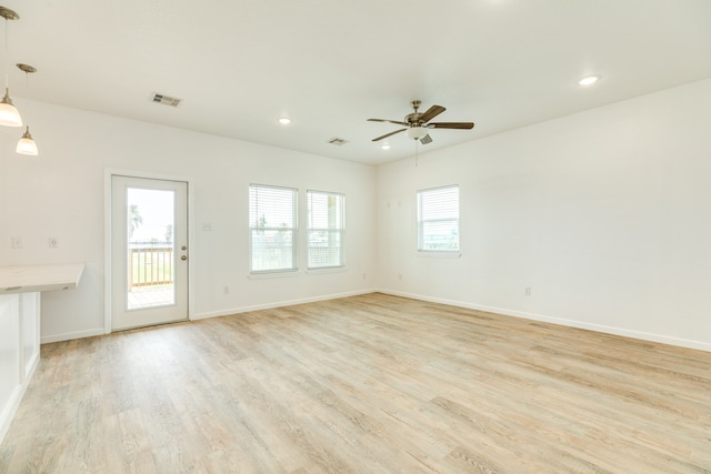 empty room with ceiling fan and light hardwood / wood-style flooring