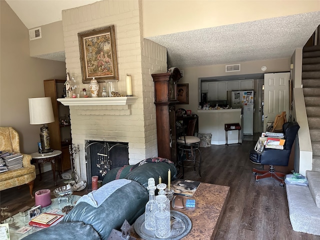 living room with a textured ceiling, a brick fireplace, and dark wood-type flooring