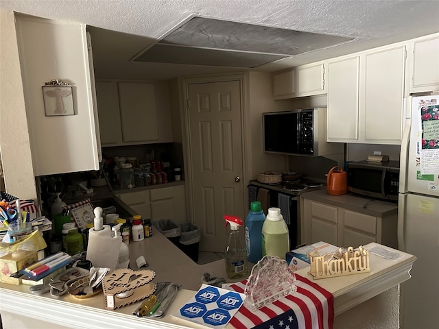 kitchen featuring white cabinetry, a textured ceiling, and white fridge