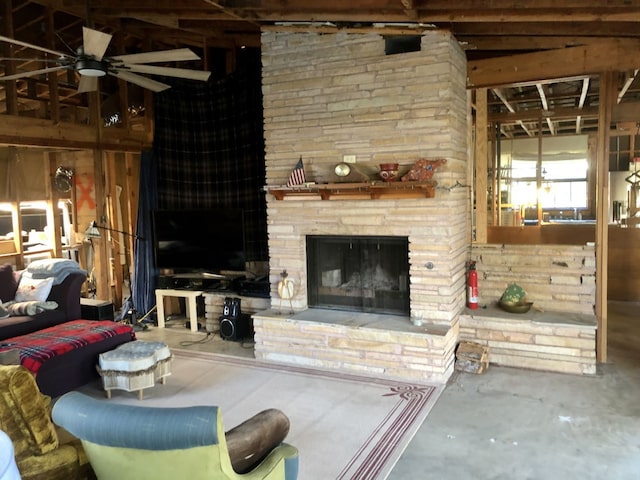 unfurnished living room featuring concrete floors, vaulted ceiling, a stone fireplace, and ceiling fan