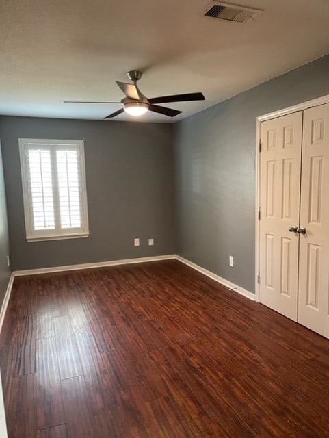 empty room with ceiling fan and dark hardwood / wood-style flooring