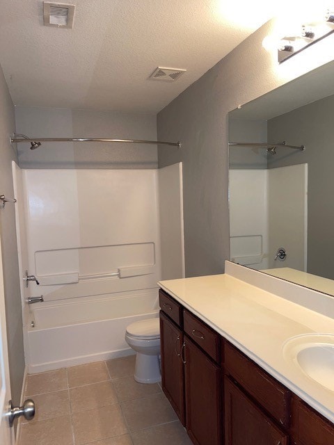 full bathroom with a textured ceiling, vanity, tile patterned flooring, toilet, and washtub / shower combination