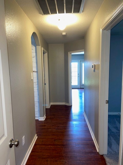 hall with dark wood-type flooring and a textured ceiling