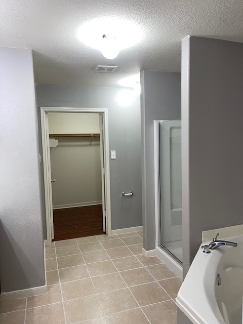 bathroom featuring a textured ceiling, independent shower and bath, and tile patterned floors