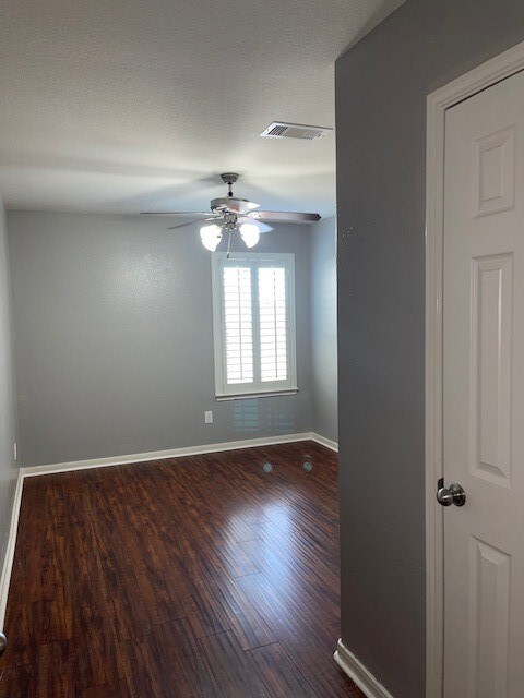 empty room featuring ceiling fan, wood-type flooring, and a textured ceiling