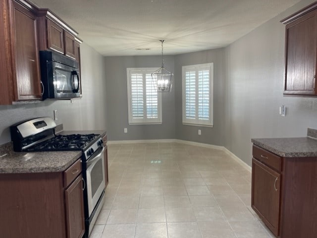 kitchen with a chandelier, stainless steel gas stove, and light tile patterned flooring