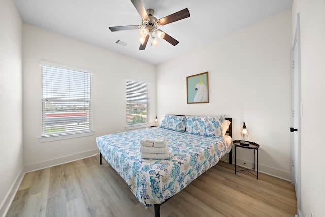 bedroom with multiple windows, light hardwood / wood-style floors, and ceiling fan