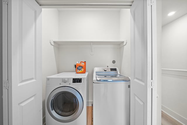 clothes washing area with light hardwood / wood-style flooring and washer and dryer