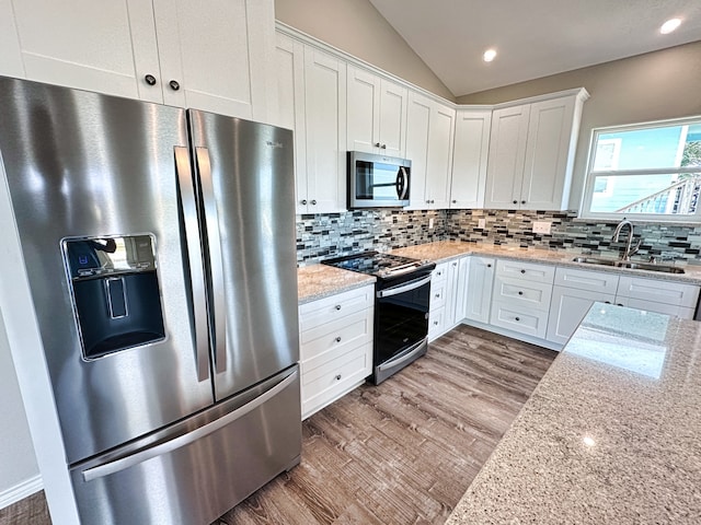 kitchen featuring appliances with stainless steel finishes, backsplash, white cabinetry, and light hardwood / wood-style floors