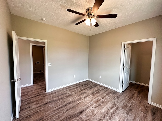 empty room with a textured ceiling, ceiling fan, and dark hardwood / wood-style flooring