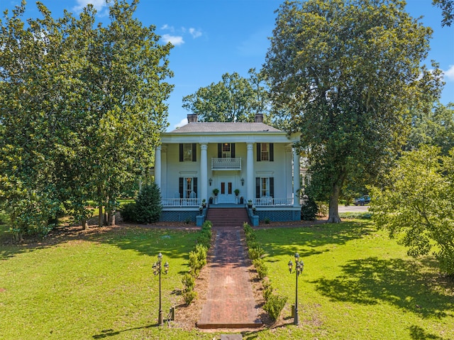 greek revival house featuring french doors, a balcony, a porch, and a front lawn