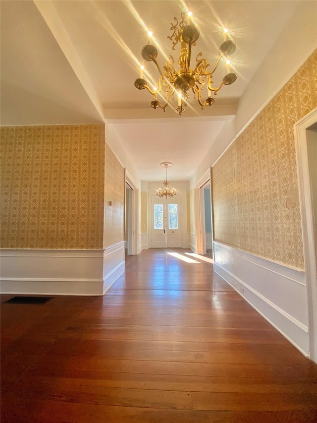 interior space with beam ceiling, wood-type flooring, and a notable chandelier