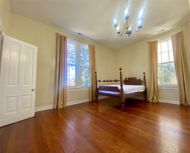 bedroom featuring dark hardwood / wood-style flooring, multiple windows, and a notable chandelier