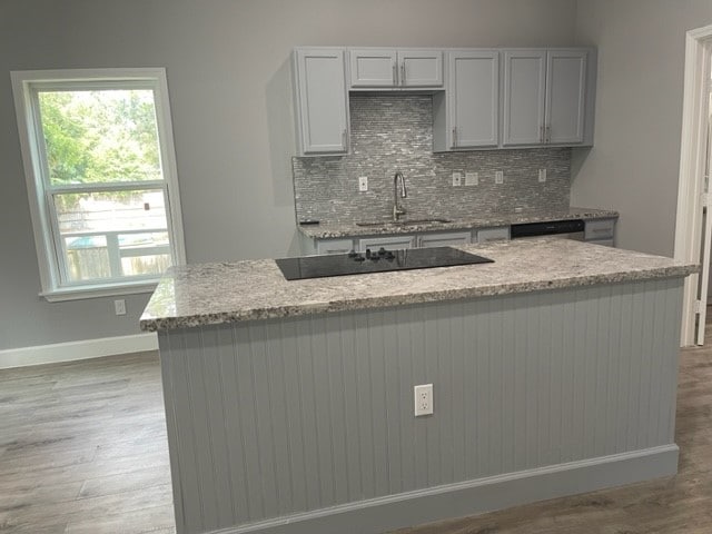 kitchen featuring black electric cooktop, light wood-type flooring, tasteful backsplash, sink, and gray cabinets