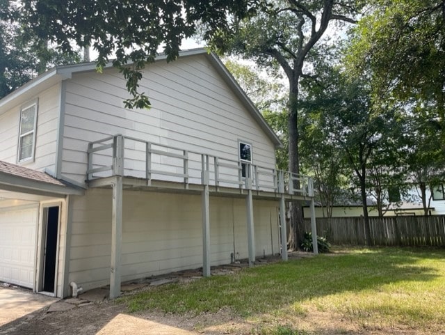 rear view of property featuring a yard, a deck, and a garage