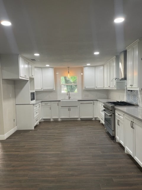 kitchen featuring wall chimney range hood, dark wood-type flooring, sink, and white cabinets