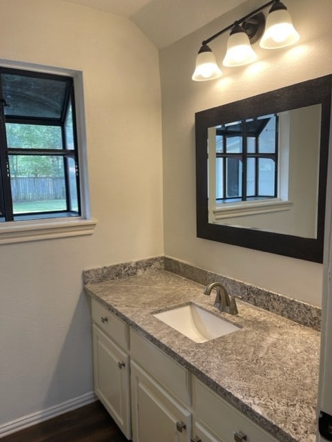 bathroom featuring vanity, hardwood / wood-style floors, and vaulted ceiling