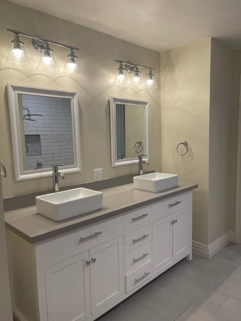 bathroom with tile patterned floors, walk in shower, vanity, and a textured ceiling