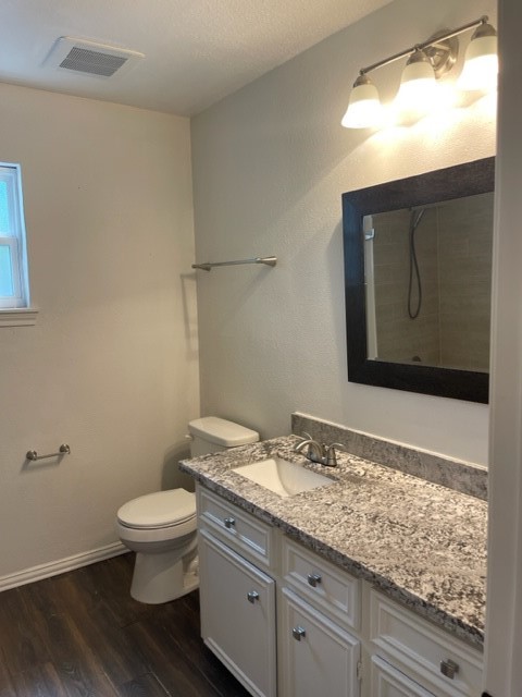 bathroom featuring vanity, wood-type flooring, a textured ceiling, walk in shower, and toilet