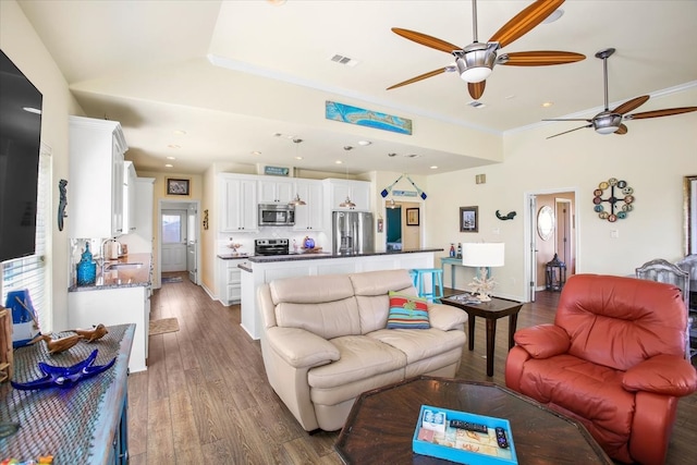 living room featuring ceiling fan, crown molding, sink, and hardwood / wood-style floors