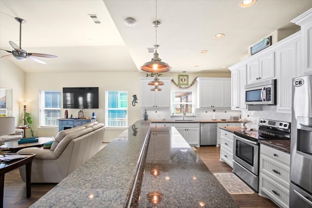 kitchen featuring white cabinets, backsplash, a healthy amount of sunlight, and stainless steel appliances