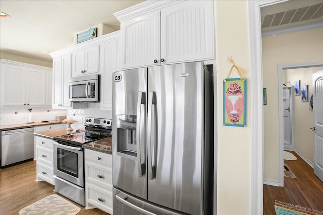 kitchen featuring stainless steel appliances, backsplash, hardwood / wood-style floors, and white cabinets