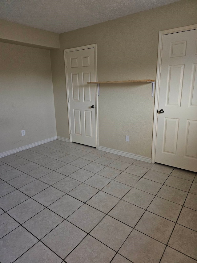 unfurnished room with light tile floors and a textured ceiling