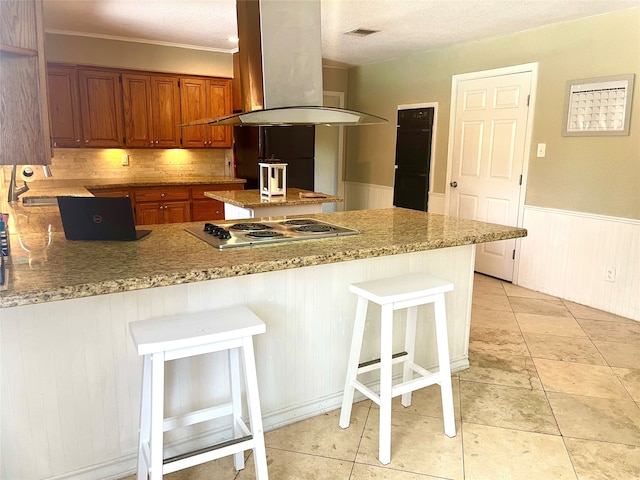 kitchen with stainless steel gas cooktop, backsplash, a kitchen bar, light tile floors, and island exhaust hood