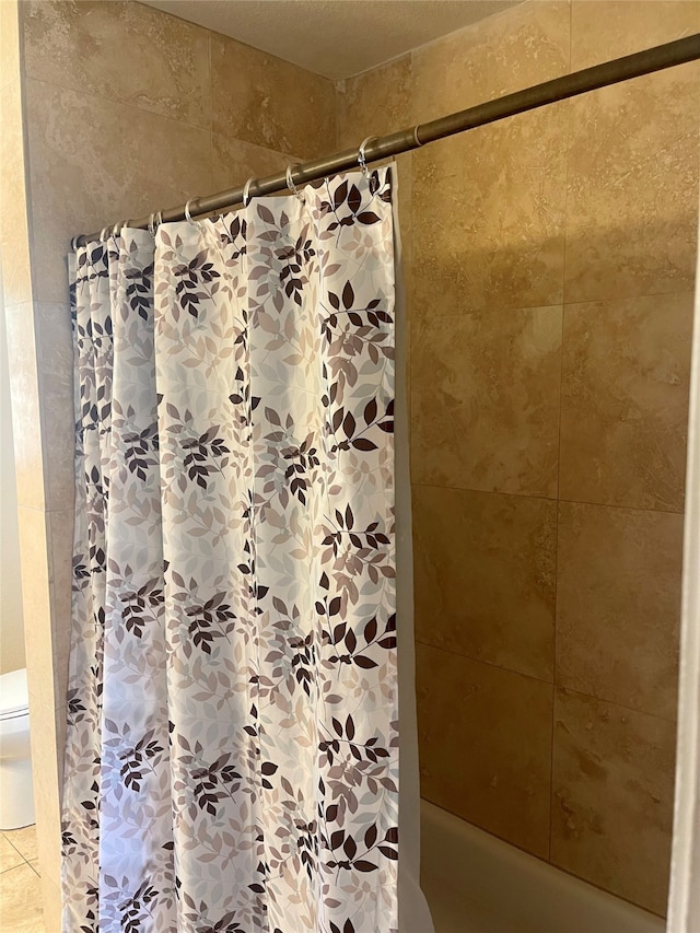 bathroom with shower / bathtub combination with curtain and toilet