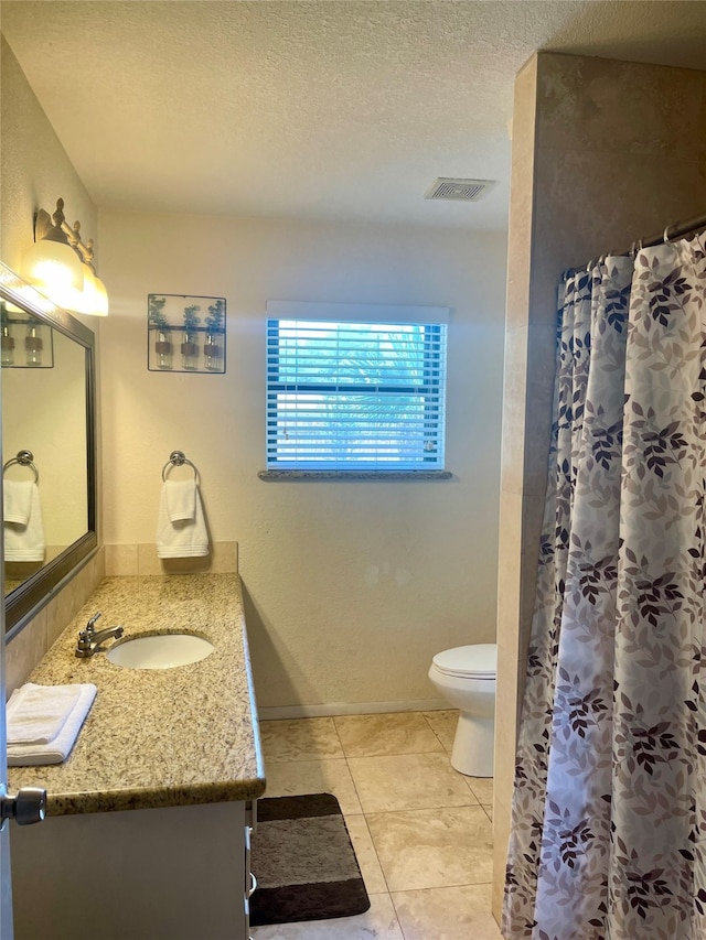 bathroom with tile flooring, toilet, vanity, and a textured ceiling