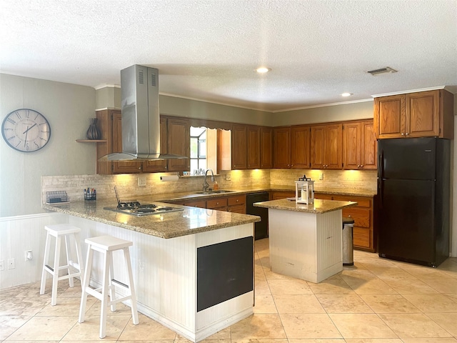 kitchen with kitchen peninsula, black appliances, a kitchen bar, fume extractor, and tasteful backsplash