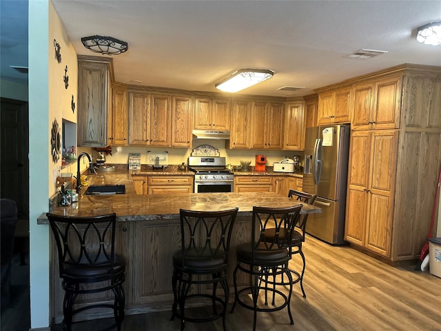 kitchen with a kitchen bar, light wood-type flooring, sink, and stainless steel appliances