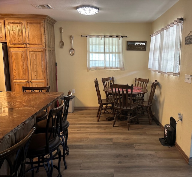 dining room featuring bar area, a healthy amount of sunlight, and dark wood-type flooring