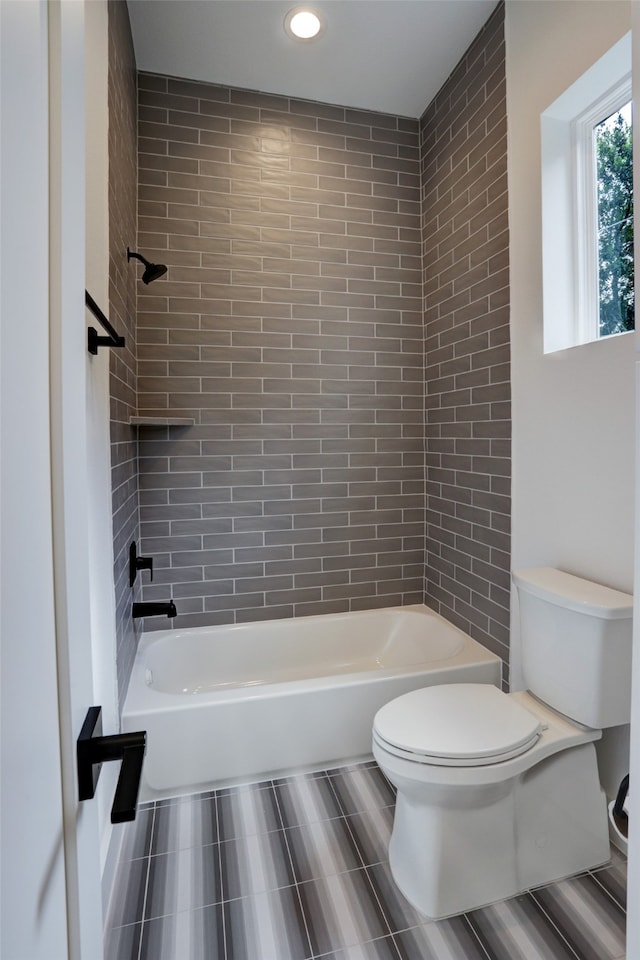 bathroom with toilet, tile flooring, and tiled shower / bath combo