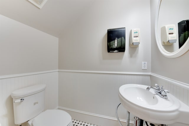 bathroom with toilet, tile floors, sink, and lofted ceiling