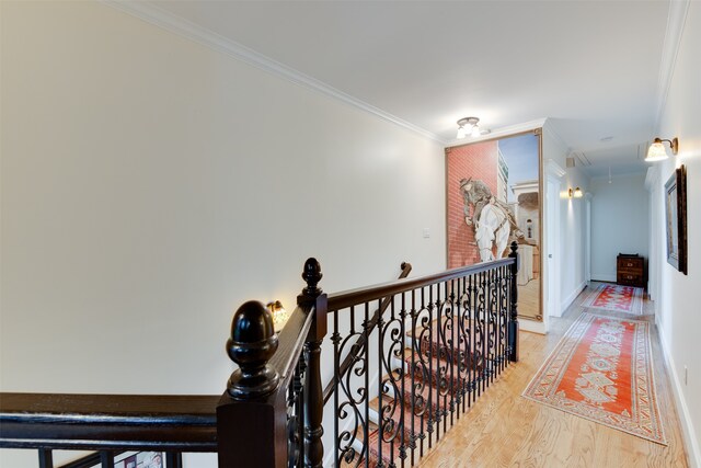 stairway with brick wall, ornamental molding, and light hardwood / wood-style flooring