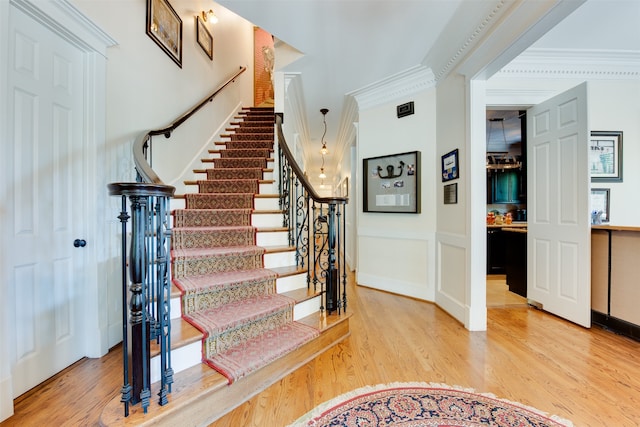 stairs with light hardwood / wood-style floors and ornamental molding