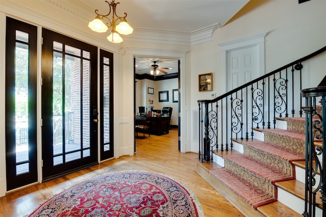 foyer with crown molding, light hardwood / wood-style floors, and ceiling fan with notable chandelier