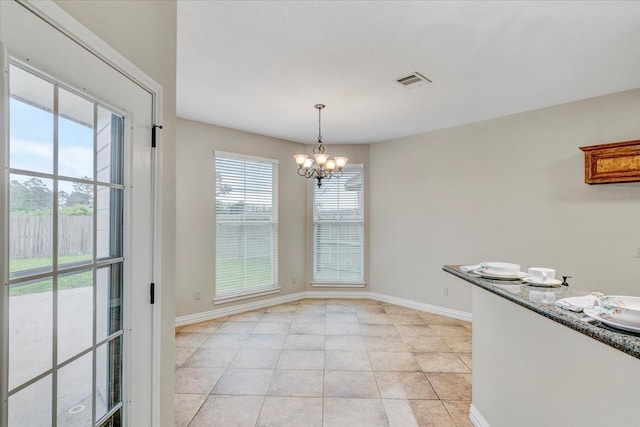 unfurnished dining area with a wealth of natural light, a chandelier, and light tile floors