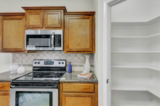 kitchen with appliances with stainless steel finishes, tasteful backsplash, and dark stone countertops