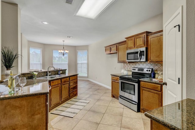 kitchen with appliances with stainless steel finishes, decorative light fixtures, a chandelier, sink, and light tile flooring